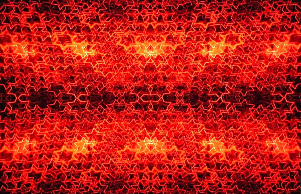 A fiery red image of hundreds of red glowing stars on a black background. The stars have so many layers in some parts of the image that it almost becomes a block colour.
